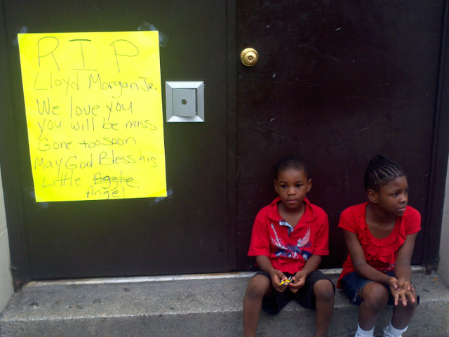 Children sit at a memorial for 4-year-old Lloyd Morgan Monday afternoon, July 23, 2012.