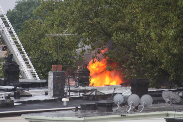 Flames are seen shooting from the roof of 3250 Fulton St., near Euclid Avenue.