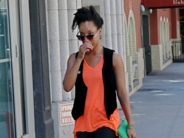 Mixing of fabric weights, textures and seasons in a light neon orange top rock and roll black velvet vest and green Louis Vuitton on 13th Street west Village.