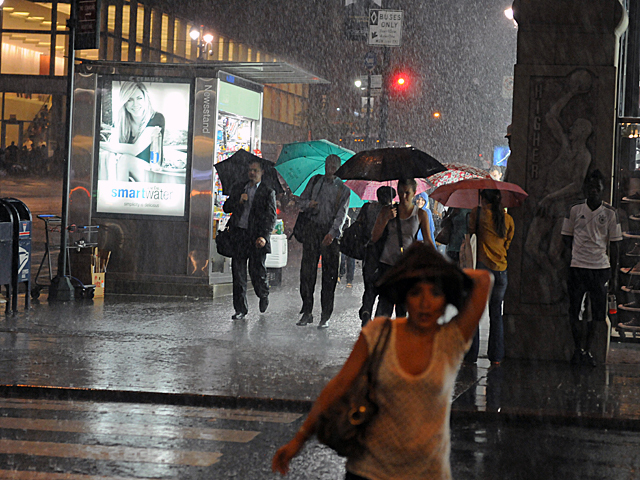 People rushed through the heavy rain near Grand Central Terminal July 26, 2012. 