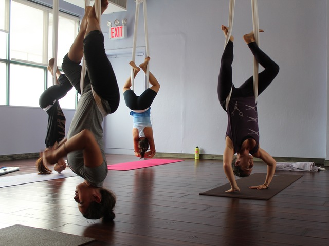 Participants practice various traditional yoga poses while suspended a few inches above the ground.