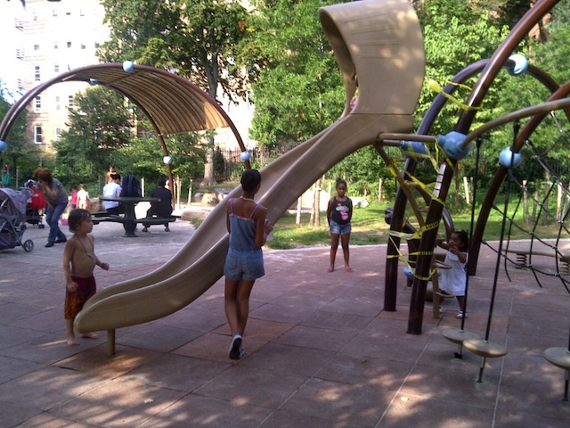 Children play near the newly installed slide at Indian Road playground at Inwood Hill Park.