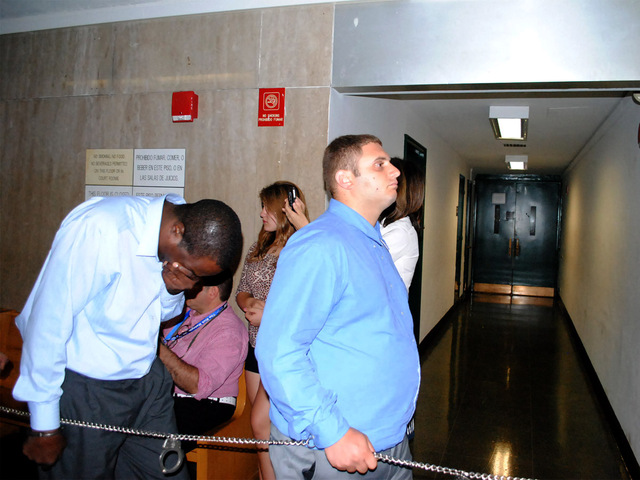 Andrew Douglas covers his face with his hand while he and Anthony Pellegrino, who faced an additional charge of official misconduct, enter court on Monday August 20, 2012. 