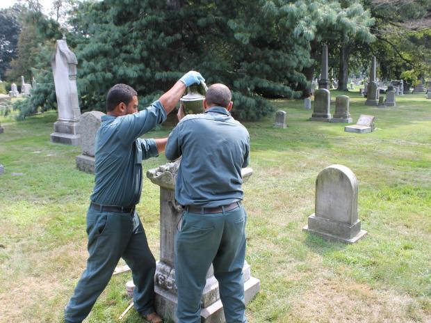 Workers repair one of the monuments damaged at Green-Wood Cemetery in August 2012.