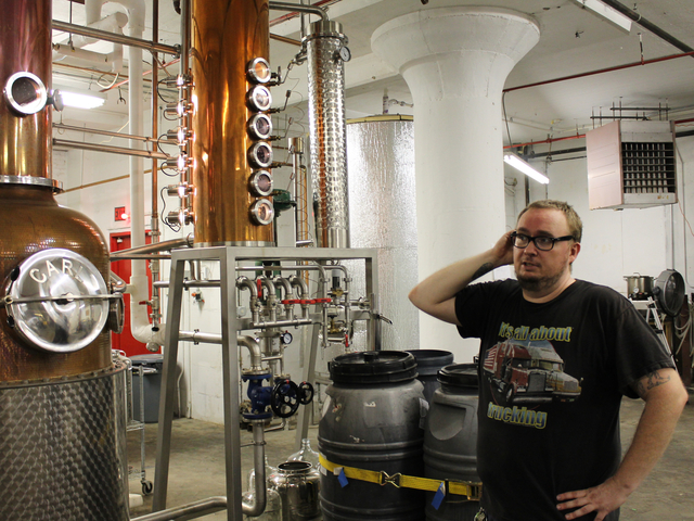 Assistant distiller David Lewis stands in front of Van Brunt Stillhouse's handmade copper stills.