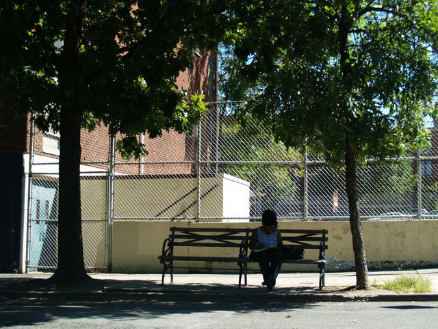 A woman enjoys the shade of two nearby trees on 78th Street.