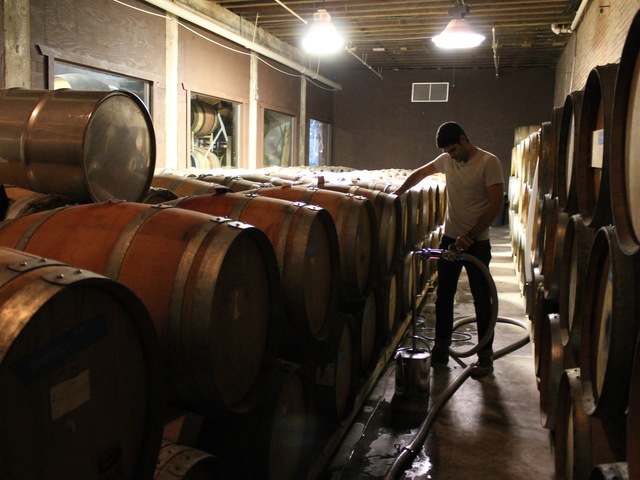 Red Hook Winery cellar master Ben Nicholas tops-off casks of wine.