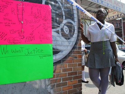 A young girl stands beside a makeshift memorial for Reynaldo Cuevas who was shot and killed across the street on Friday September 7, 2012. 