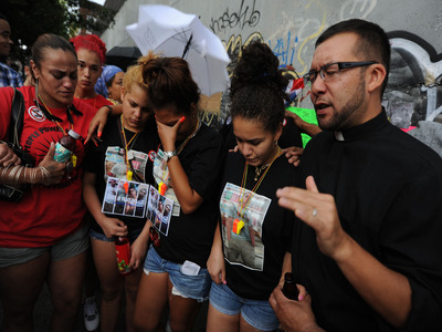 The Rev. Ruben Austria leads a brief prayer service during vigil.  From left in black shirts:  Reynaldo's cousin Massiel Cuevas, friend Gizelle Guzman and cousin Ashley Cuevas. 