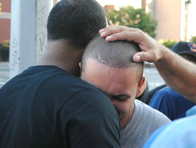 Friends console Joel Cuevas, 26, at the site of a memorial where his brother Reynaldo, 20, was shot on September 7, 2012. 