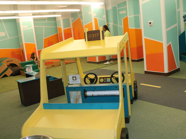 <p>The indoor play space features a taxi and buildings to play on.</p>
