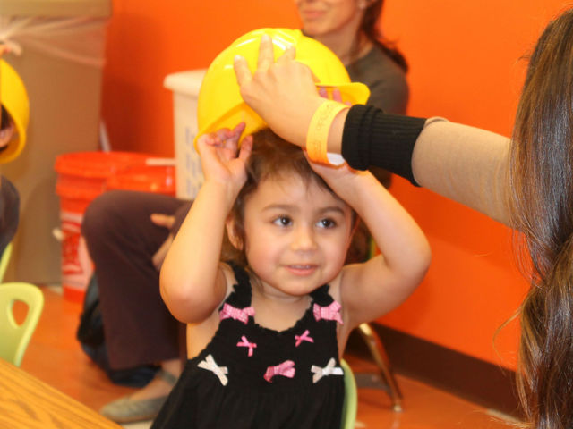 <p>Jennah, 3, tries on her hard hat at Apple Seeds.</p>
