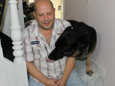 Joseph Butrico and his dog Maxwell inside their Marine Park Home. The city fined Butrico after neighbors complained about Max's excessive barking.