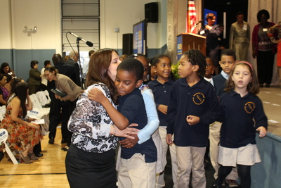 A student gets a hug from his teacher after performing during a welcoming at Teachers College Community School.