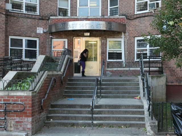 A woman stands outside of 308 E. 145th St.