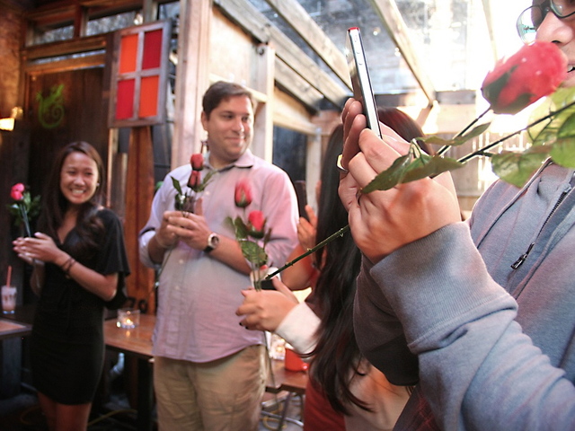 Family and friends wait with roses to greet the newly engaged couple.  