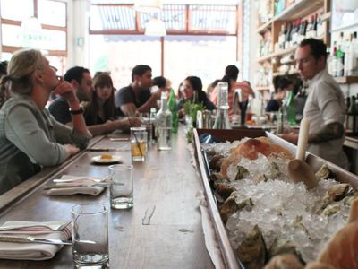 The open kitchen at the end of one of the bars at Jeffrey's Grocery provides plenty of entertainment as kitchen staff shuck oysters. 