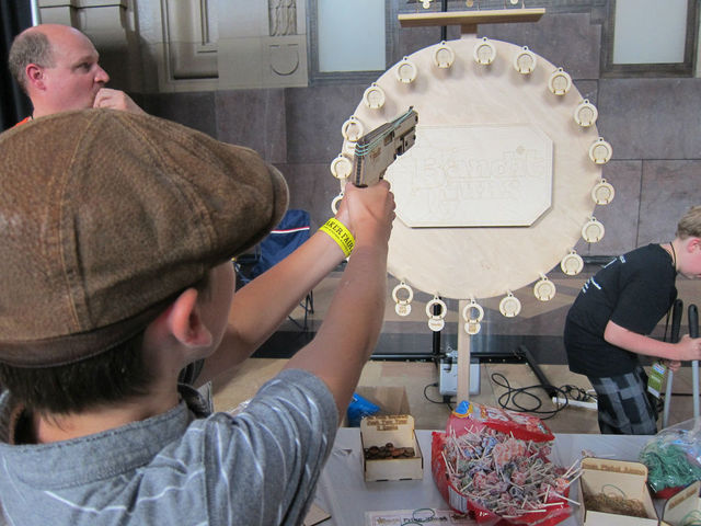 A kid plays with a rubberband gun at Maker Faire.
