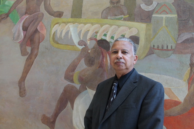 Vertis Hayes Jr. in front of a pane of his father's work 