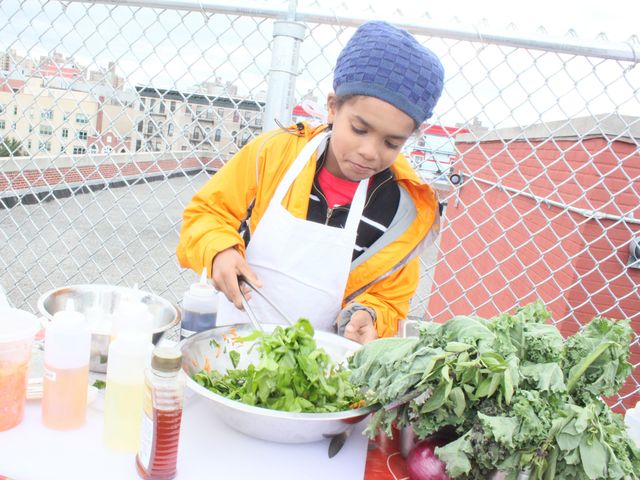 <p>Malik Shahia, a fourth-grader from the Earth School, serves up a salad made with produce mostly from the Fifth Street Farm.</p>
