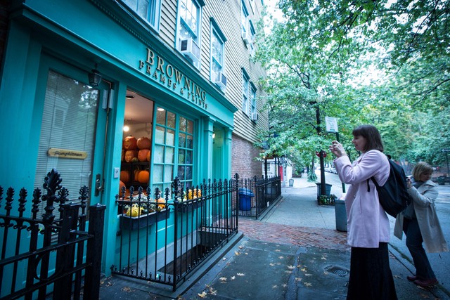<p>Passer-bys take pictures of McMahon carving pumpkins in his studio.</p>

