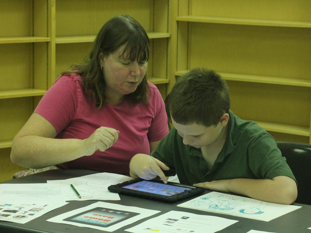 <p>Mary Cusack and her son Nicky work on a story during the Autism Initiatives iPad storytelling class at the Forest Park Library on Oct. 1, 2012.</p>
