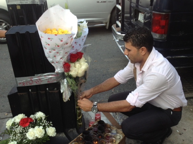 <p>Ashraf Selim, co-owner of The Ice Lounge, places flowers at a memorial for Noel Polanco, who worked at bar. Polanco was shot to death by an NYPD detective on Oct. 4, 2012.</p>
