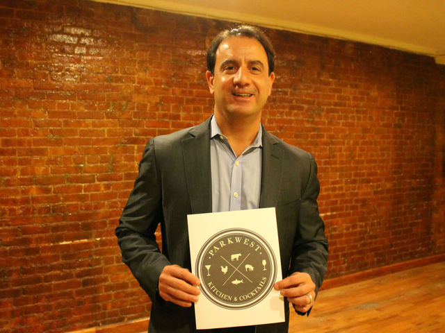 <p>Peter Coundouris holds up the logo of his new restaurant venture, Park West at 103 W. 70th St.</p>
