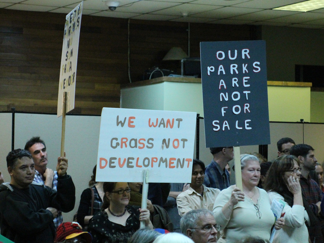 <p>Residents hold signs protesting the planned development for Flushing Meadows Corona Park.</p>
