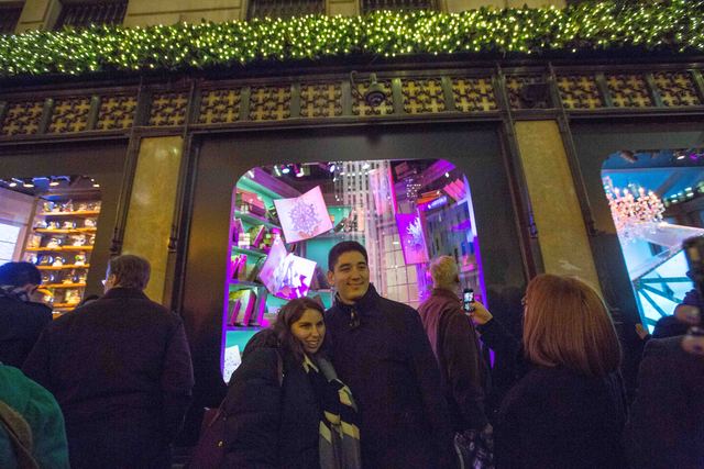 <p>Visitors take pictures in front of the Saks' windows on Nov. 19.</p>
