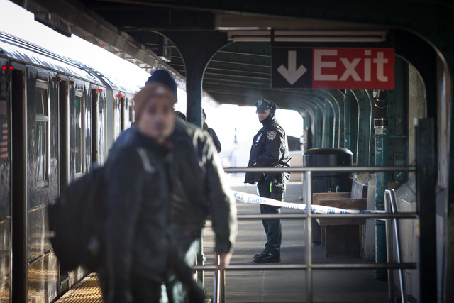 <p>Subway riders exit a 7 train at 40th Street Station in Sunnyside as a police officer stands watch Friday morning, Dec. 28, 2012.</p>
