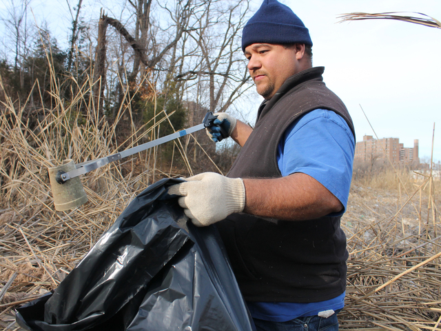 <p>Edwards Santos picks up trash along the Sherman Creek shoreline.&nbsp;</p>
