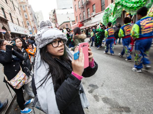 <p>A young girl takes pictures of the New York United Lion and Dragon Dance Troupe at the annual East Meets West Parade in Chinatown & Little Italy on Dec. 22nd, 2012.</p>