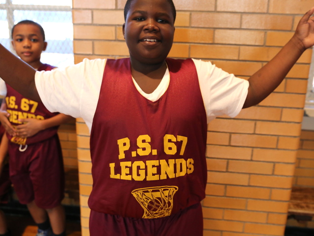 <p>A young boy shows off his new jersey before a P.S. 67 basketball game.</p>
