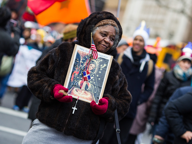 <p>A woman holds a holy icon and the American flag during the 36th Annual Three Kings Day Parade in East Harlem on Jan. 4, 2013.</p>
