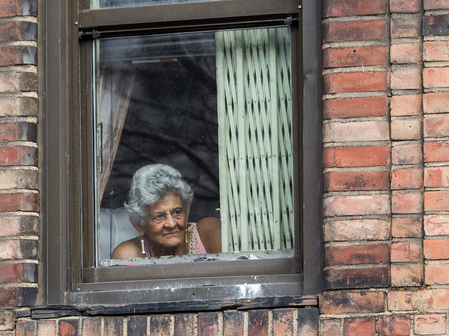 <p>A woman takes in the Annual Three Kings Day Parade from her apartment window in East Harlem on Jan. 4, 2013.</p>

