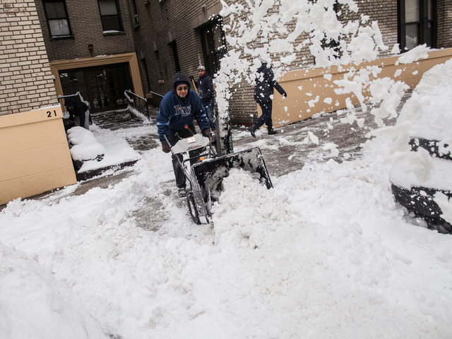 <p>Building workers in Washington Heights use a snow blower to clear a sidewalk of snow on Bennett Ave after a the city was hit with 11 inches of snow on Feb. 9, 2013.</p>
