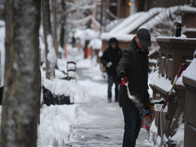 <p>A man tosses salt down on the sidewalk after the snowstorm on Feb. 9, 2013.</p>

