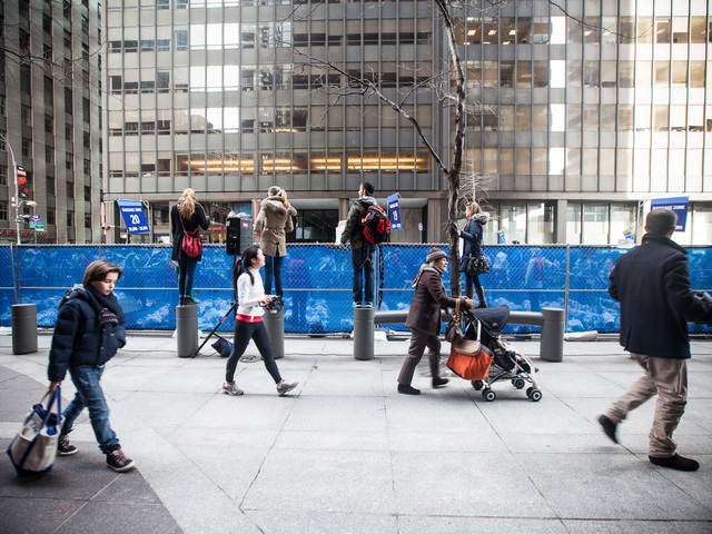 <p>Spectators perch on sidewalk columns to view runners heading for the finishing line of the annual NYC Half marathon on Mar. 17, 2013.</p>
