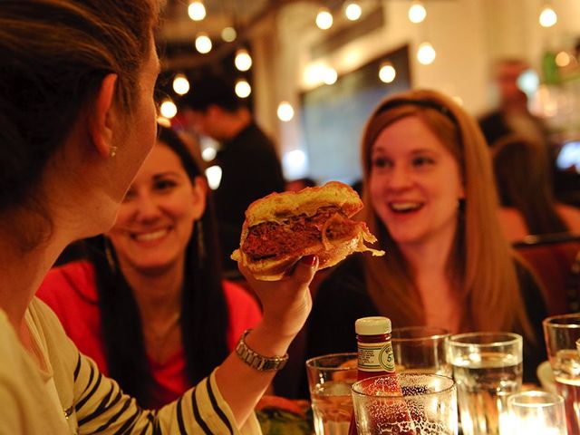 <p>Customers enjoy a burger at 5 Napkin Burger.</p>
