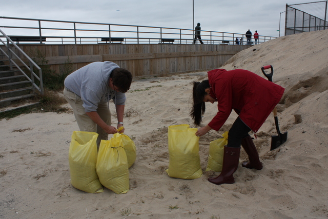 <p>Brendan and Bianca Brosh pack bags full of sand at Rockaway Beach for securing their home during Hurricane Sandy, on October 28, 2012.</p>
