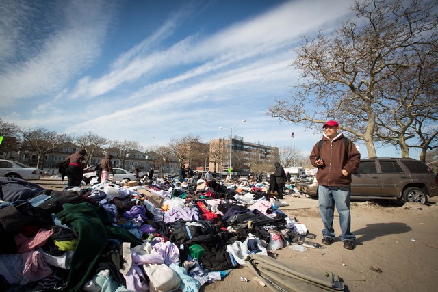 <p>Eddie Pizarro, 54, a tow truck driver stands next to a mountain of donated clothes in the Rockaways after Hurricane Sandy. He has been boiling water on his stove to keep warm at his apartment.</p>
