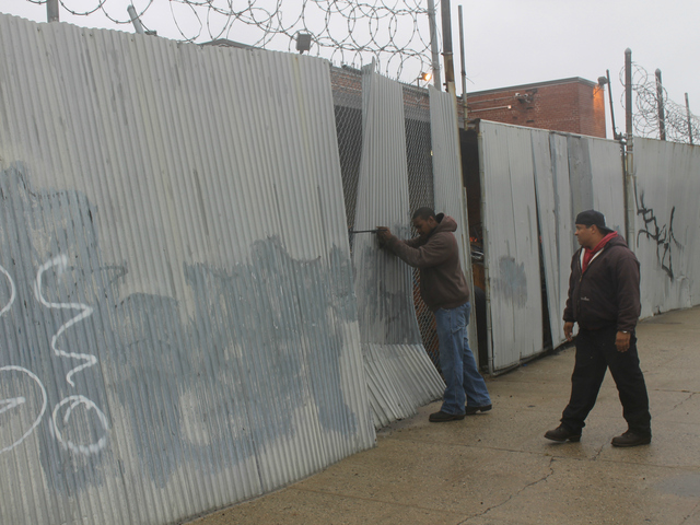 <p>Verizon workers try to secure corrugated metal attached to fence outside the phone company's building on Carroll Street in Gowanus.</p>
