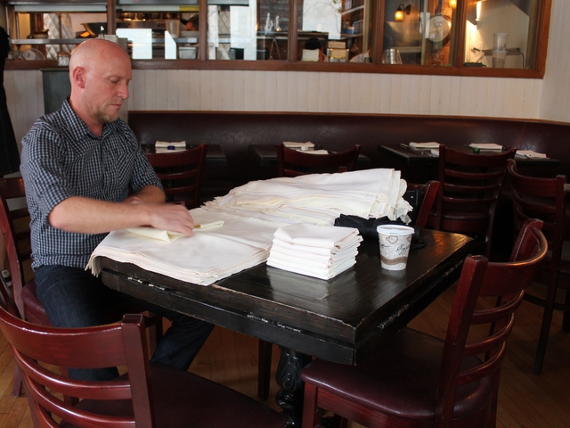 <p>A worker folds napkins at Little Owl restaurant in Greenwich Village as it got ready to open on Saturday for the first time since the power outage caused by Hurricane Sandy.</p>
