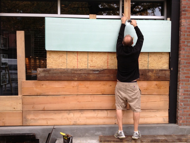 <p>Kitchen designer George Monos hangs wood planks over the front windows of Waterfront Kitchens on Van Brunt Street in Red Hook. "I was going for something classier this year," he said. "I think I nailed it. No pun intended."</p>
