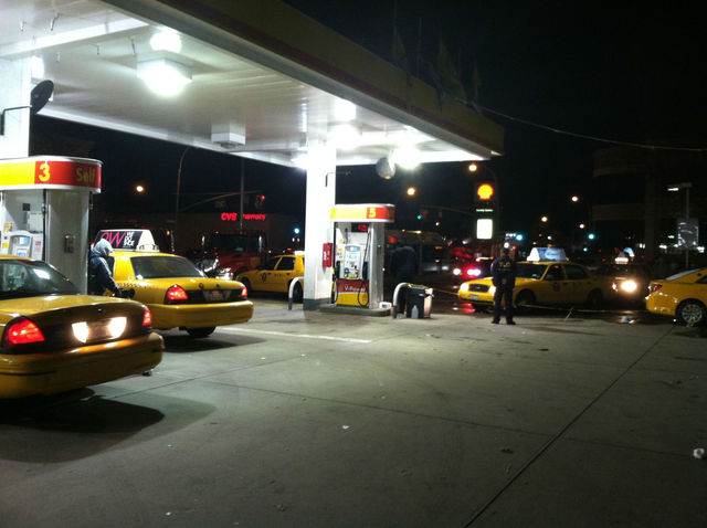 <p>A city official watches as cabs pour into the Shell Station in Jackson Heights.</p>
