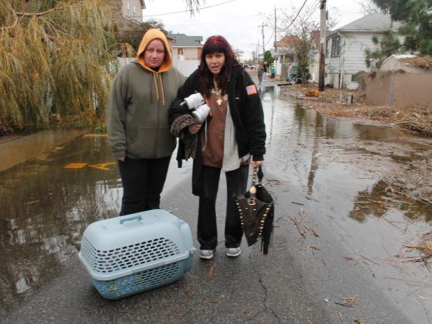<p>October 31, 2012 - Two women carry their cat from their home on Fox Beach Lane.</p>