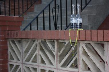  A yellow beaded necklace with a cross hangs around two empty beer bottle where Freddie Hernandez was shot. 
