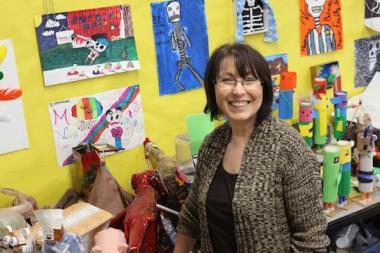  Hamilton Elementary multicultural studies art teacher Esther Pullman smiles in front of a gallery of student work. 
