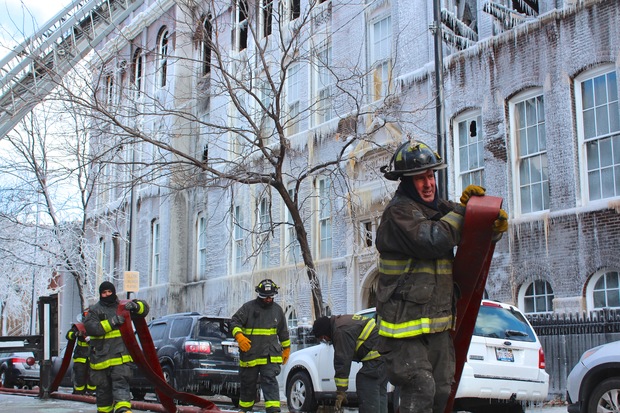  Firefighters carry hose lines in front of the former Mulligan Elementary School. 